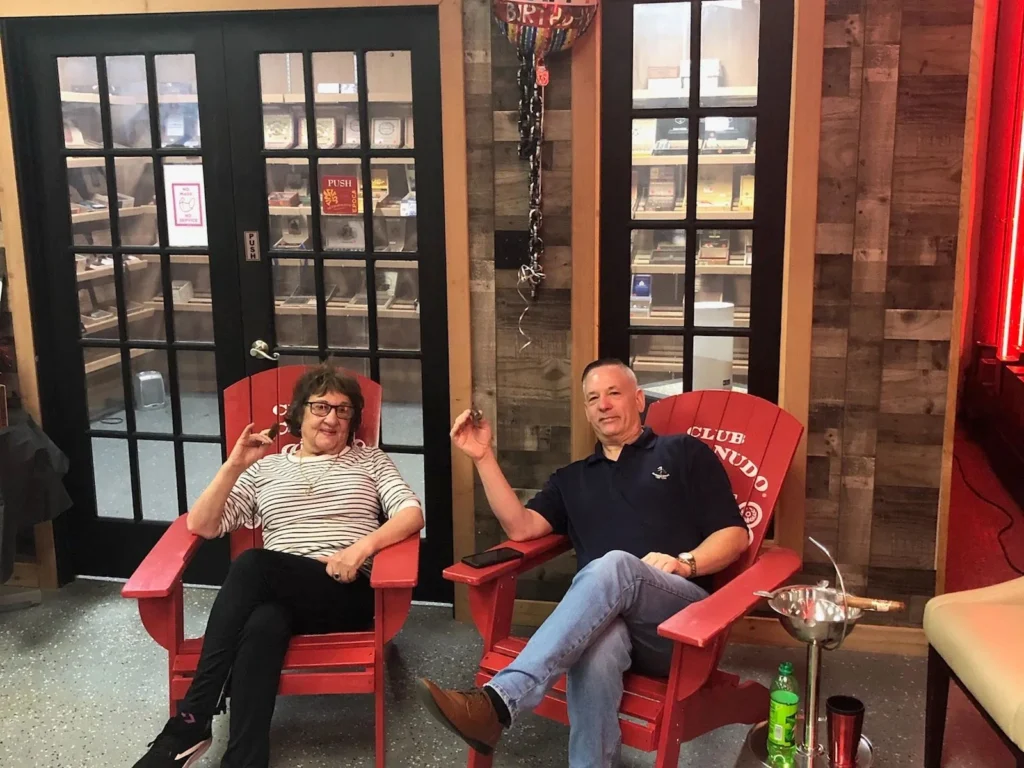 Two regulars relaxing in red Adirondack chairs outside the Castle Cigars humidor