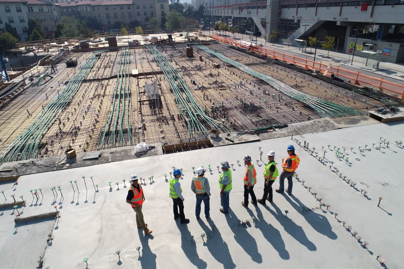 A construction crew in hard hats on a concrete deck, seen from above