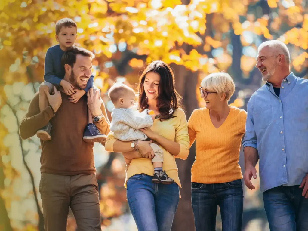 Three generations of a family walking together through autumn leaves